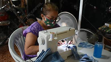 Thai old women working use sewing machine made fabric mask at workshop while Coronavirus COVID 19 outbreak and PM 2.5 Dust situati