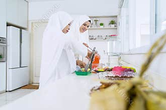 Mother and woman serving food and beverage in kitchen