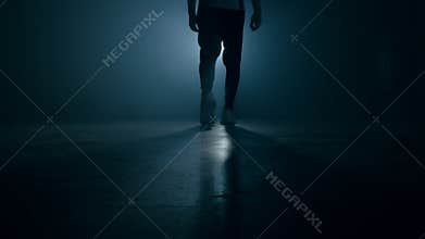 Silhouette of man legs in sports shoes sneakers is walking through smoky studio