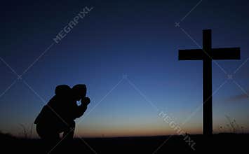 Clasped hands in prayer. Asks God. Bending his knees at the cross. A man is praying. Easter illustration.