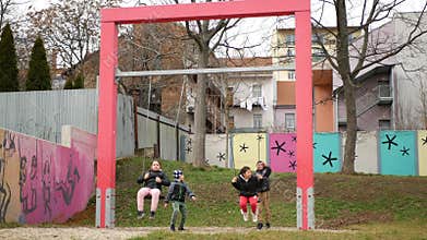 Ghetto poor in Brno, street life people children of gypsy play on swings
