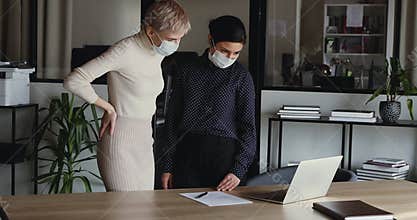 Indian and caucasian businesswomen wear masks greeting with elbow bump