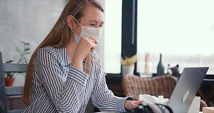 Young happy medical worker woman using laptop to work from home, consult people online on quarantine wearing face mask.