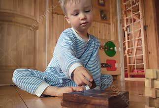Cute little child boy playing with wooden board game at home. Kid in kindergarten, nursery infant school or play room
