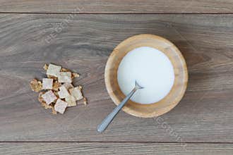 Wooden bowl with milk and dry cereal near.