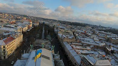 FPV drone flies over the roof of the Lviv Opera and Ballet Theater at sunset. Ukraine flag in the center of the frame