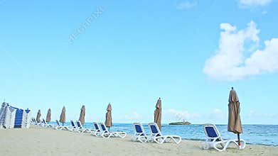 Slowly panorama at empty sandy seashore with beach chairs and closed umbrellas