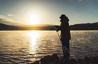 Silhouette fisherman fishing rod at sunrise sunlight, outline man enjoy hobby on evening lake, person catch fish on background