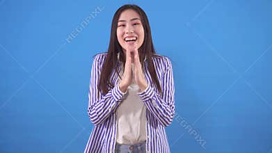 Surprised happy young asian woman on a blue background