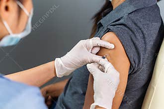 Doctor in gloves holding syringe and making injection to patient in medical mask. Covid-19 or coronavirus vaccine