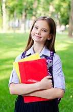 Back to school. Education concept. Cute smiling schoolgirl holding the books outdoor