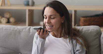 Smiling young woman talk with voice assistant on smartphone