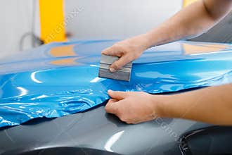Car wrapping, mechanic with squeegee installs film