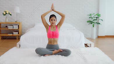 Attractive Asian woman practice yoga lotus pose to meditation in bedroom