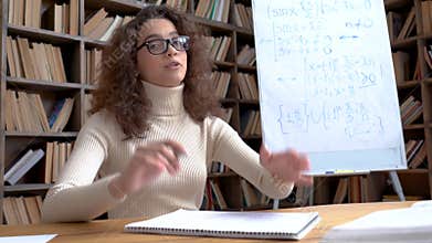 Young hispanic teacher speaking looking at camera giving distance math class.