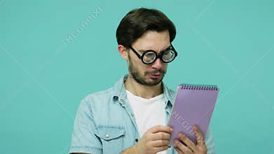 Comical weird geek in glasses studying. Clever bearded guy with round diopter eyeglasses reading notebook entries