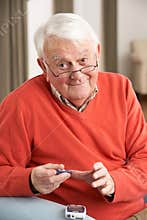 Senior Man Checking Blood Sugar Level At Home
