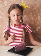Cute little girl with photoprops is blowing out candle