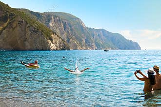 Tourists play in the sea at Chomi or Paradise Beach on the Greek Island of Corfu.