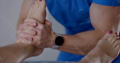 Foot massage by chiropractor in modern osteopathic clinic, masseur is massaging female feet