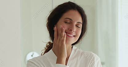 Woman in bathrobe makes facial self-massage touch skin feels happy