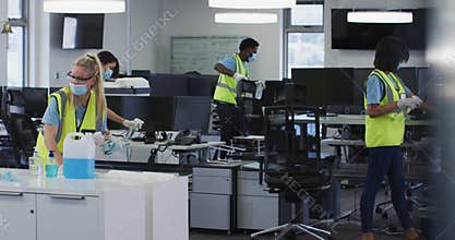 Team wearing hi vis vest and face mask cleaning the office using disinfectant