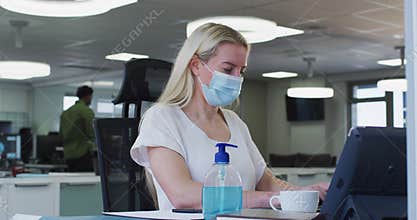 Woman wearing face mask using computer at office
