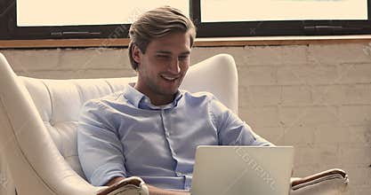 Guy sit in armchair use laptop spend time on internet
