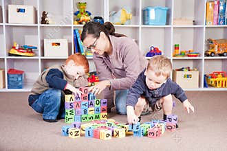 Babysitter playing kids block game with children