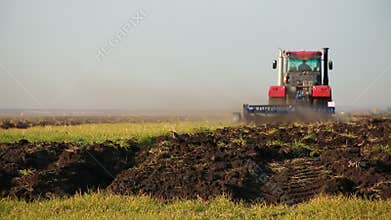 Red modern tractor with reverse plow plows the field. Agricultural work in the field, agribusiness