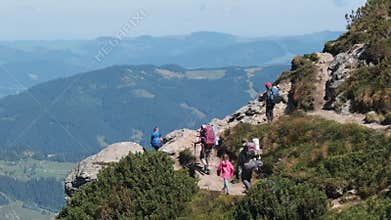 Group of Tourists and Children with Backpacks Go Down on Stone Trail in Mountain