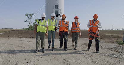 Group of engineers walking and talking on wind farm