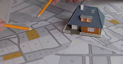 People discussing and choosing building plot for house construction on cadastral map