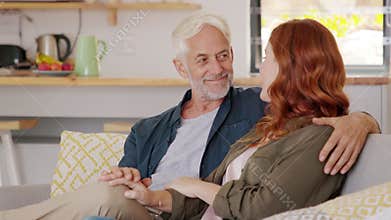 Loving mature couple embracing on couch and smiling