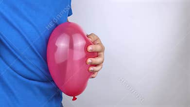 Conceptual video. The man holds a red ball near his belly, which symbolizes bloating and flatulence. Then he brings a needle to it
