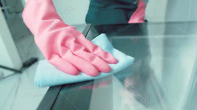 The girl cleaner wipes the door in the kitchen with a rag inside the oven.