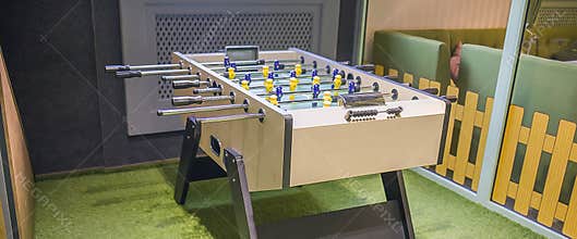 Children`s game - table football with figures of football players of both teams in a wooden box in the playroom for teenagers.