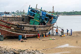 DAR ES SALAAM, TANZANIA - JANUARY 2020: Group of African Black People reparing Wooden fishing boat on the Coast of Dar