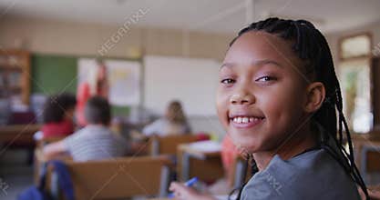 Girl smiling while sitting on her desk at school