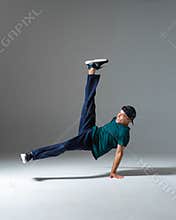 Cool b-boy dancing in studio  on gray background with copy space. Dancing school poster