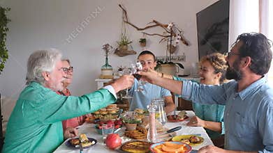 Group of people of all ages eating together at home food - happy adults and seniors togetherness - have lunch indoors - celebratin