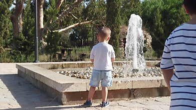 Adorable toddler watching the fountain,His brother walking towards baby