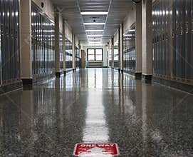 Empty high school hallway with one way sign on floor