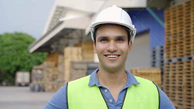 20s happy Indian distribution shipping depot worker looking at camera and smile. Male worker in hard helmet at