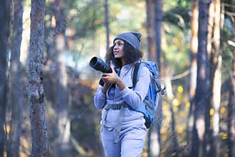 African American woman walking in the forest with a photocamera.