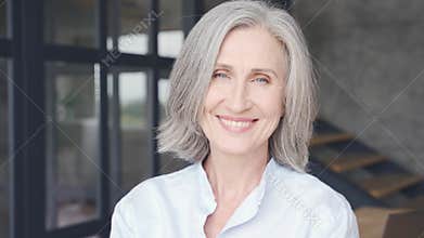 Smiling mature grey-haired woman laughing in office, close up headshot portrait.