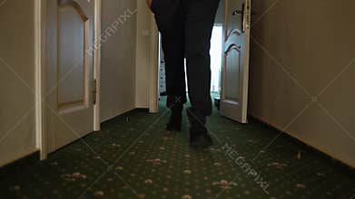 Man walking along a narrow corridor with a green carpet, close-up
