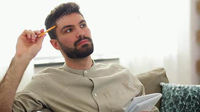 Man writing to notebook and thinking at home