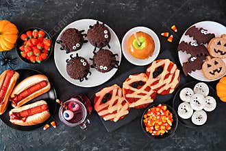 Halloween party food table scene top view over a black stone background