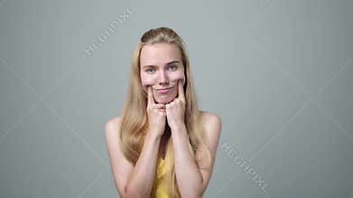 Young woman making fake smile with fingers stretching the corners of her mouth